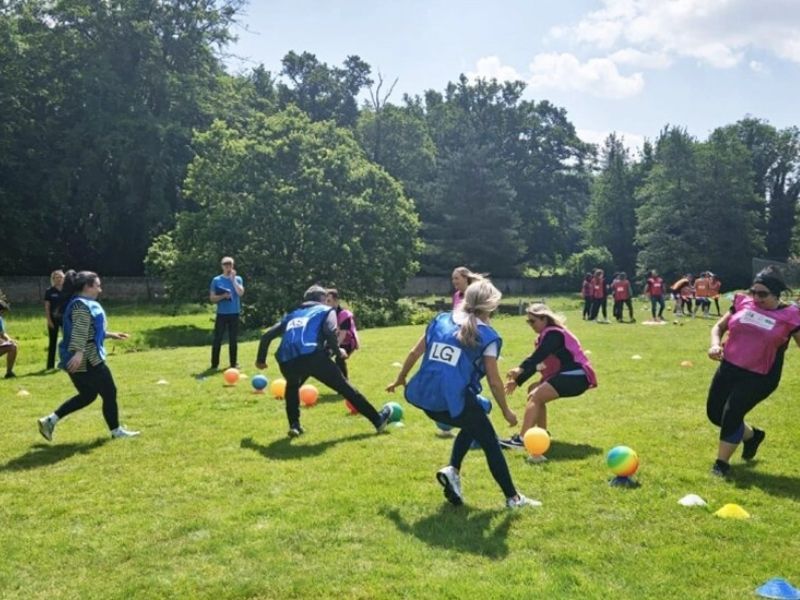 Equipos con petos compitiendo por los balones en una pradera