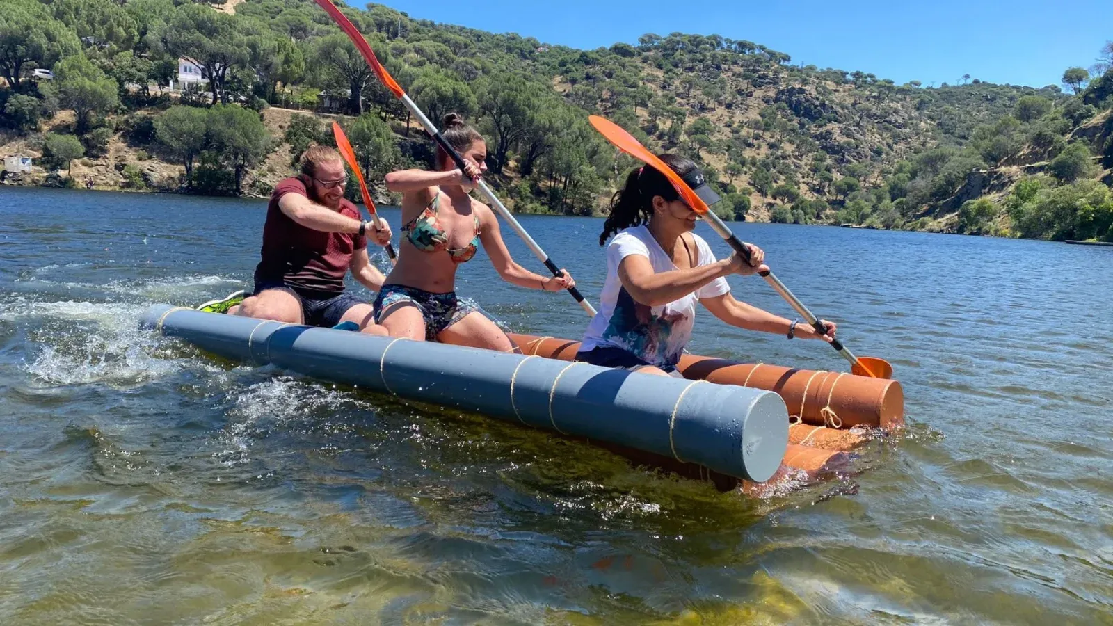 Tres personas remando sobre una balsa hecha con bidones