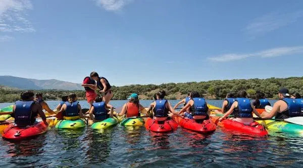 Grupo remando en piraguas unidas en fila por un embalse