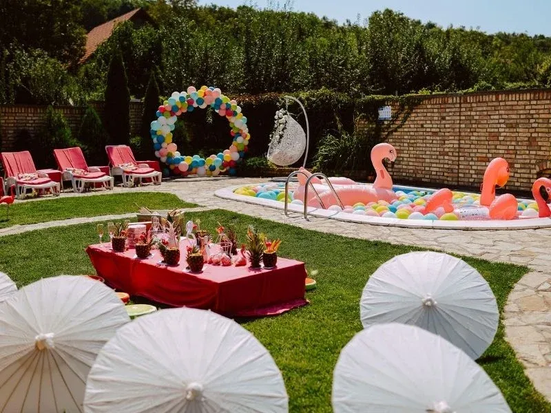 Zona de piscina decorada con flamencos y sombrillas para una fiesta de plantilla