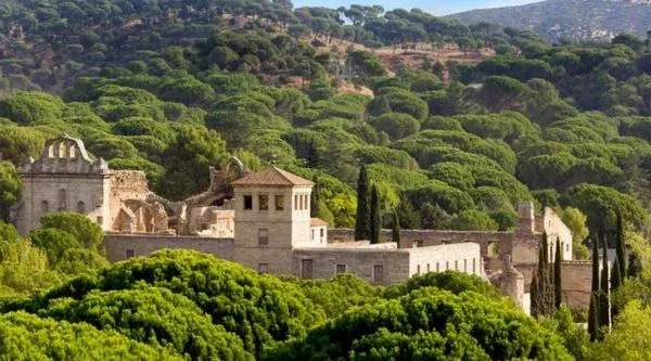 Monasterio de piedra entre pinares visto desde la ladera de enfrente preparado para un evento de empresa